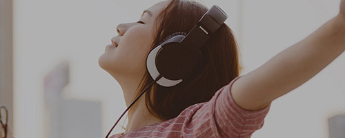 Woman with headphones on, arms outstretched