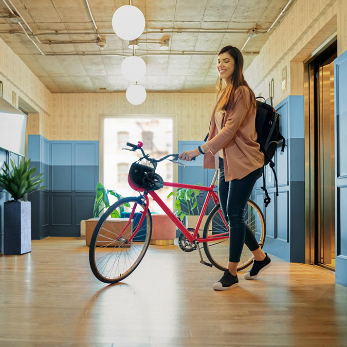 Woman walking a bike out of an elevator