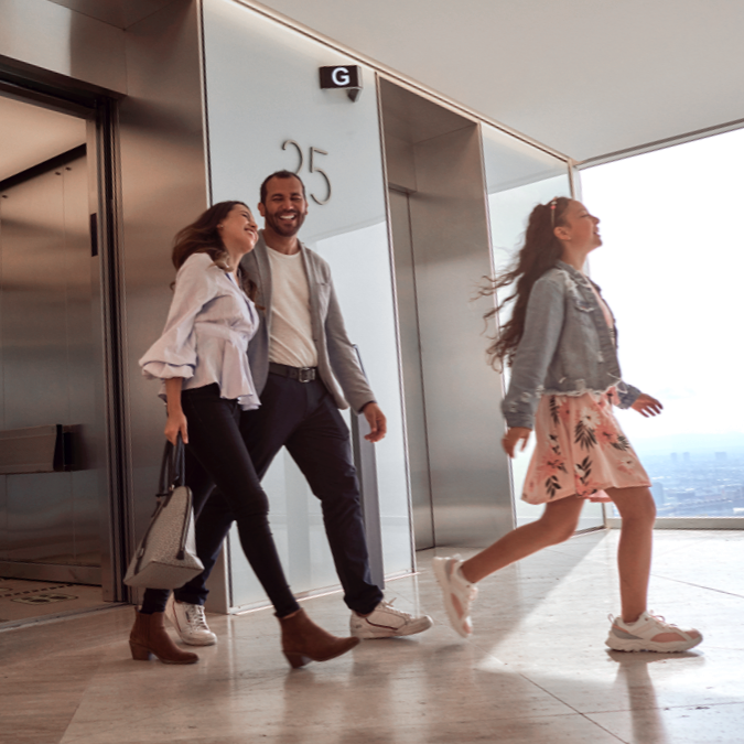 People smiling as they walk out of an elevator